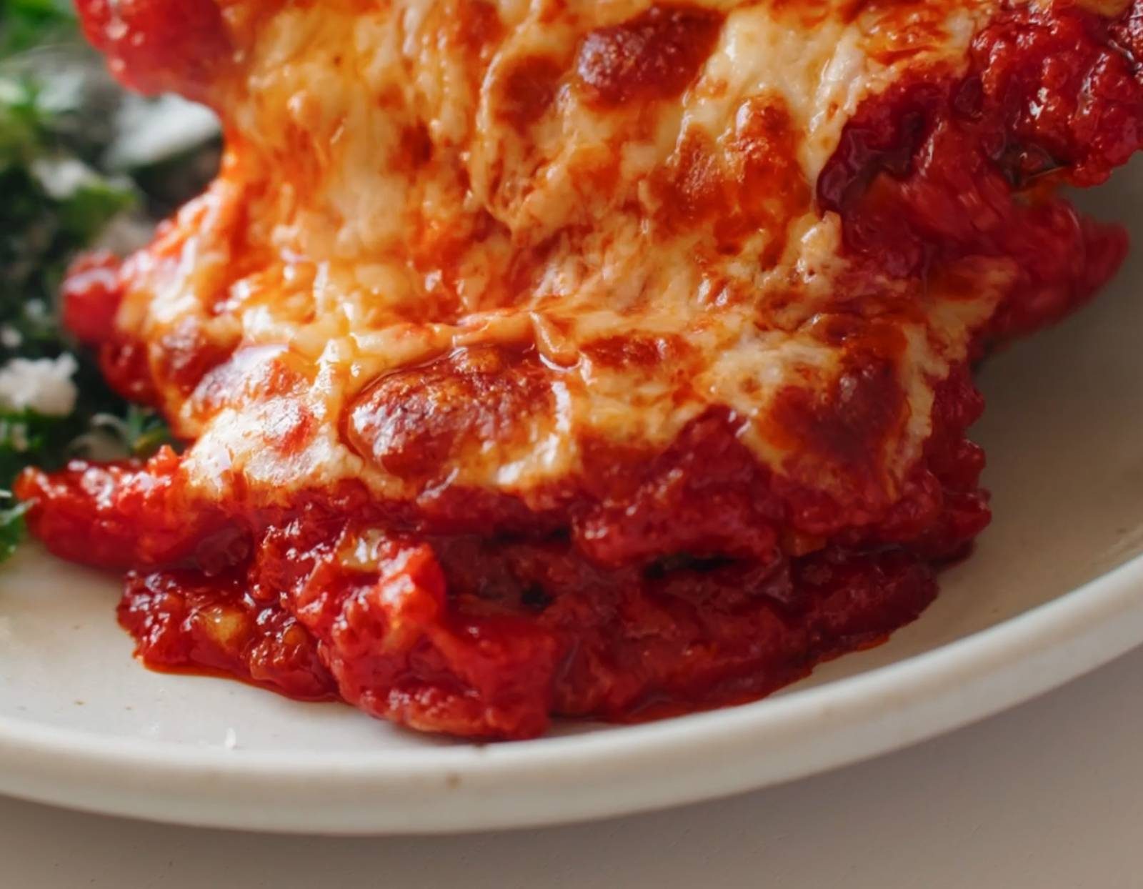Pouring cheese over chicken.