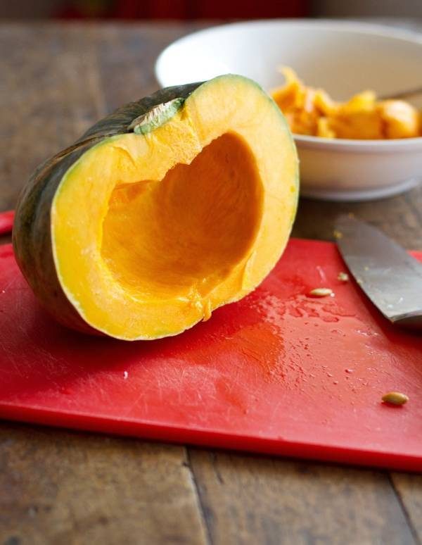 Kabocha squash cleaned of it's seeds on a red cutting board.