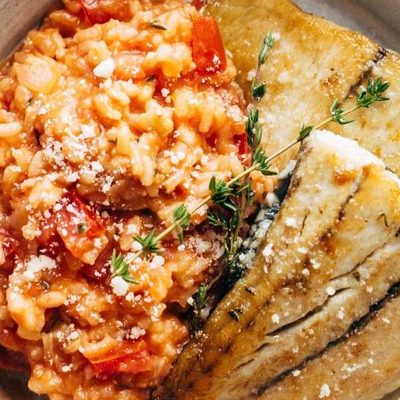 Barrumundi fish with tomato risotto on a plate.