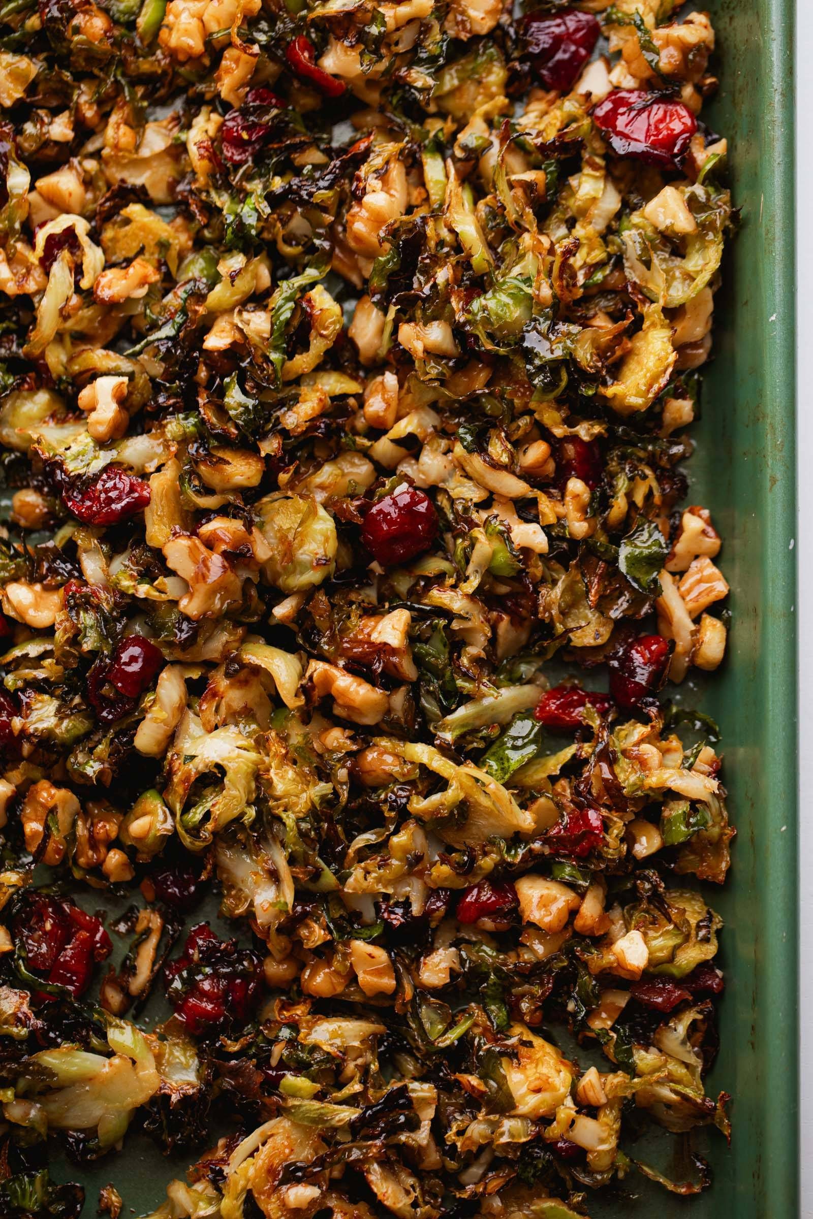Brussels sprouts on a sheet pan with cranberries and gochujang butter.