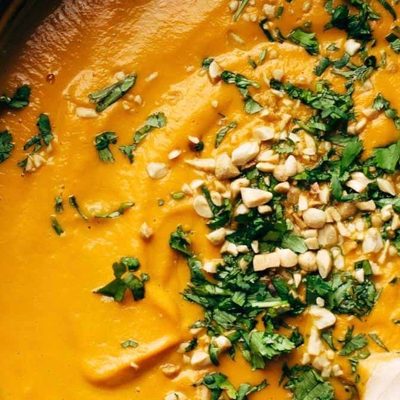 Spicy Carrot Soup in pot with wooden spoon.