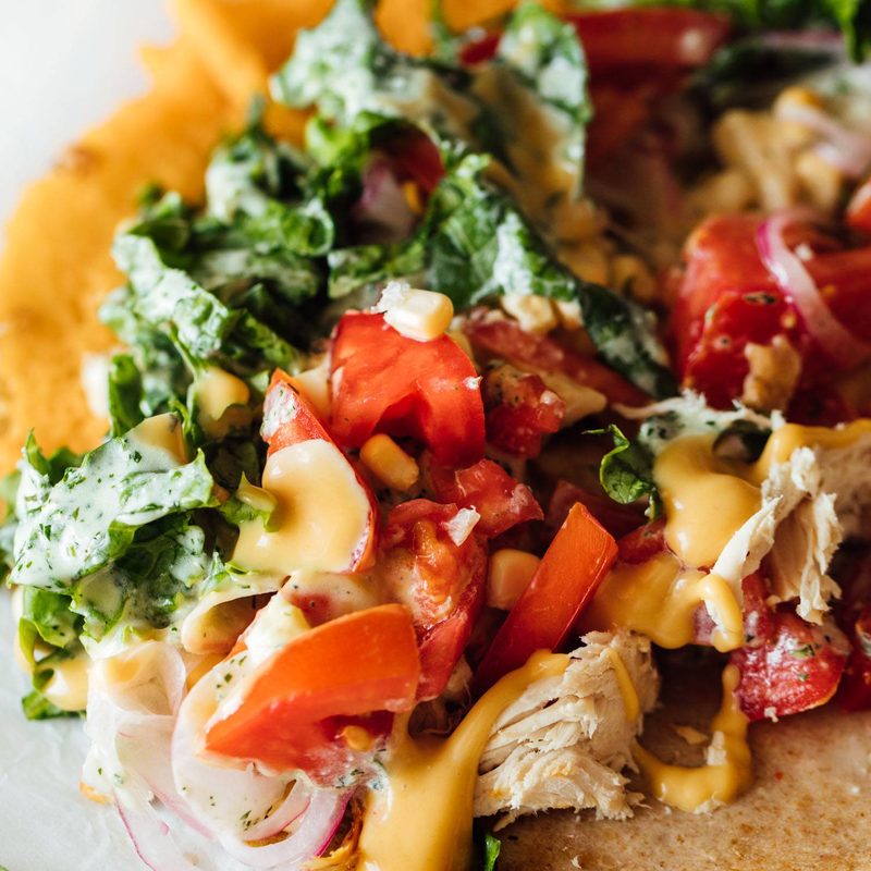 Close up of a saucy chicken wrap with toppings.