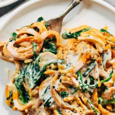 Creamy Spinach and Sweet Potato Noodles on a plate with a fork.