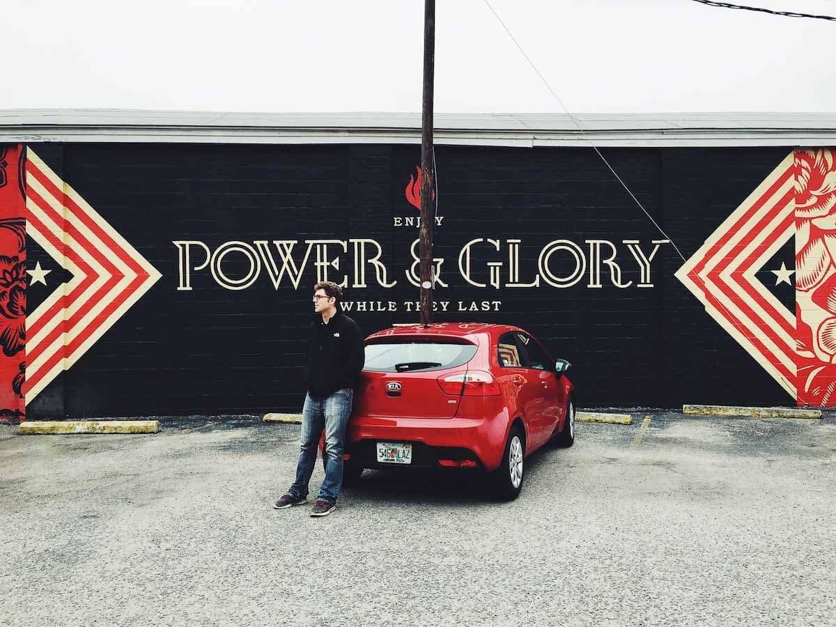man standing next to a red car